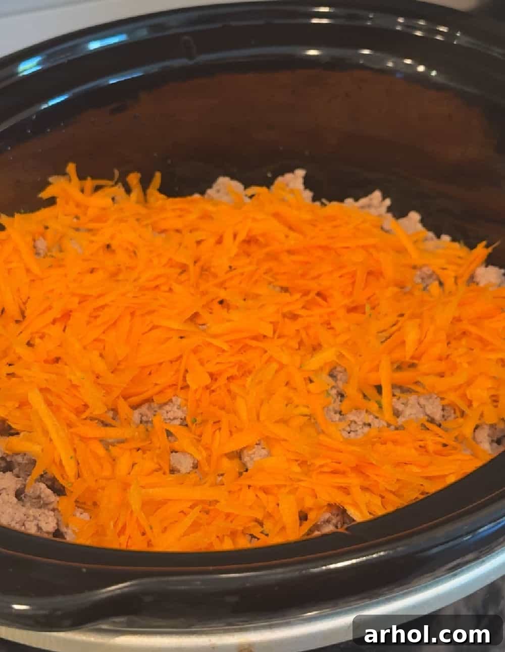 Grated carrots sprinkled over the turkey and vegetables in the crockpot.