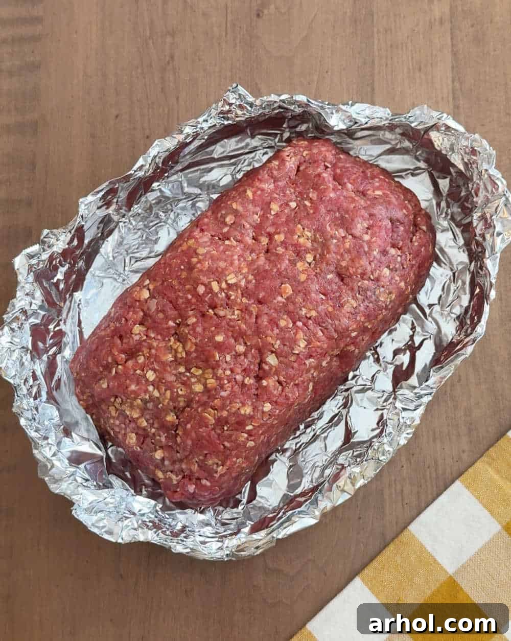 A meatloaf formed and placed on aluminum foil, ready for the slow cooker.