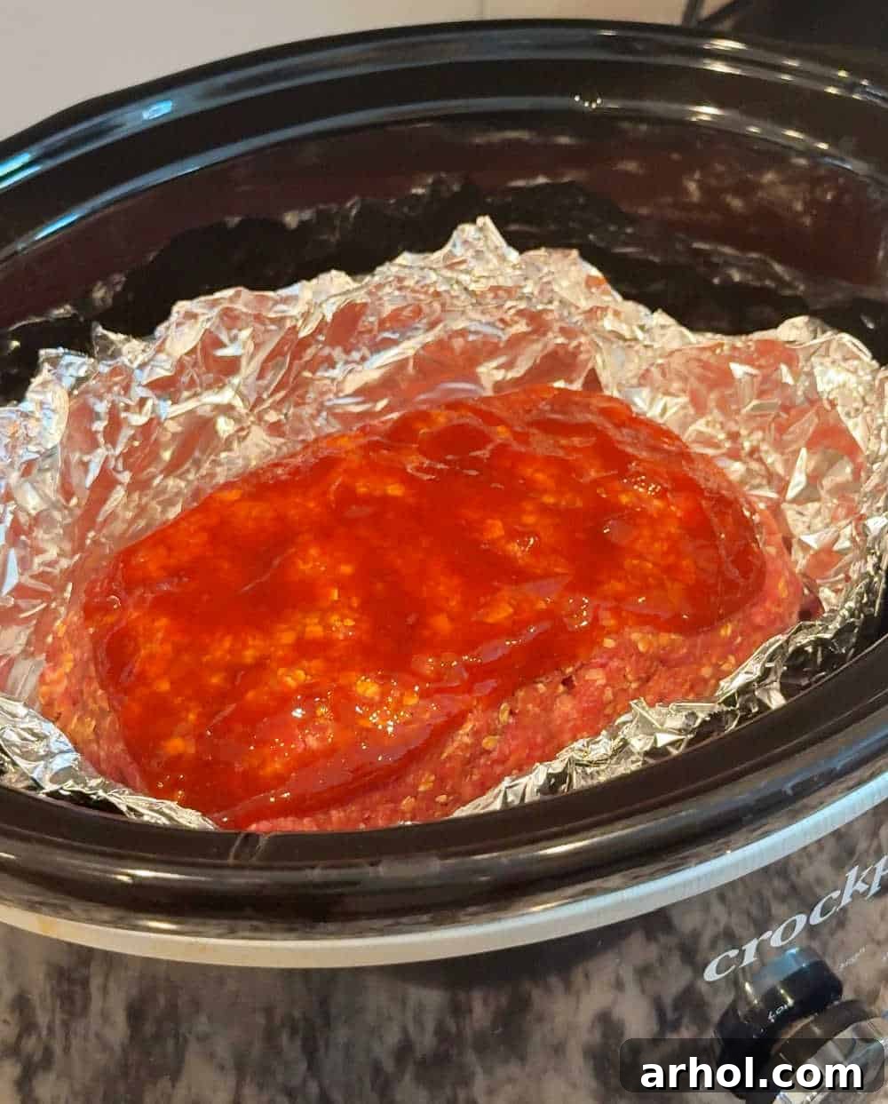 A glazed meatloaf cooking inside a slow cooker, looking perfectly moist.