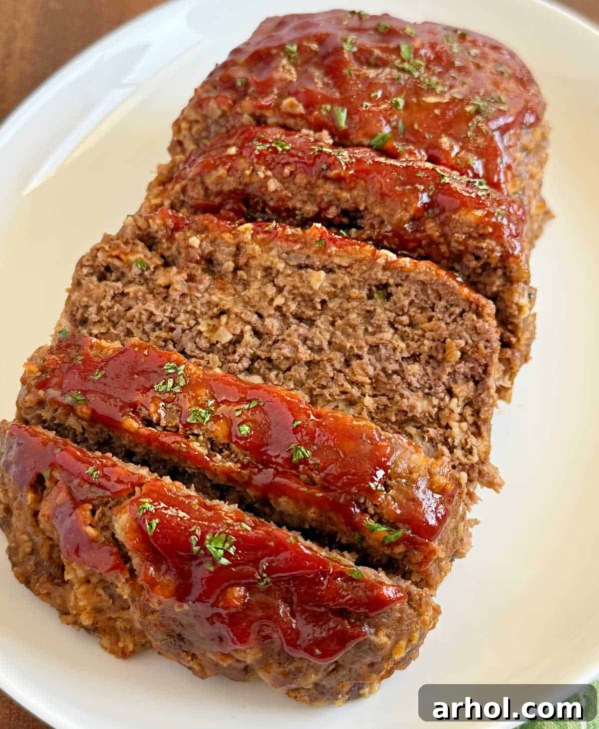 Perfectly sliced slow cooker meatloaf on a white platter, ready for serving.