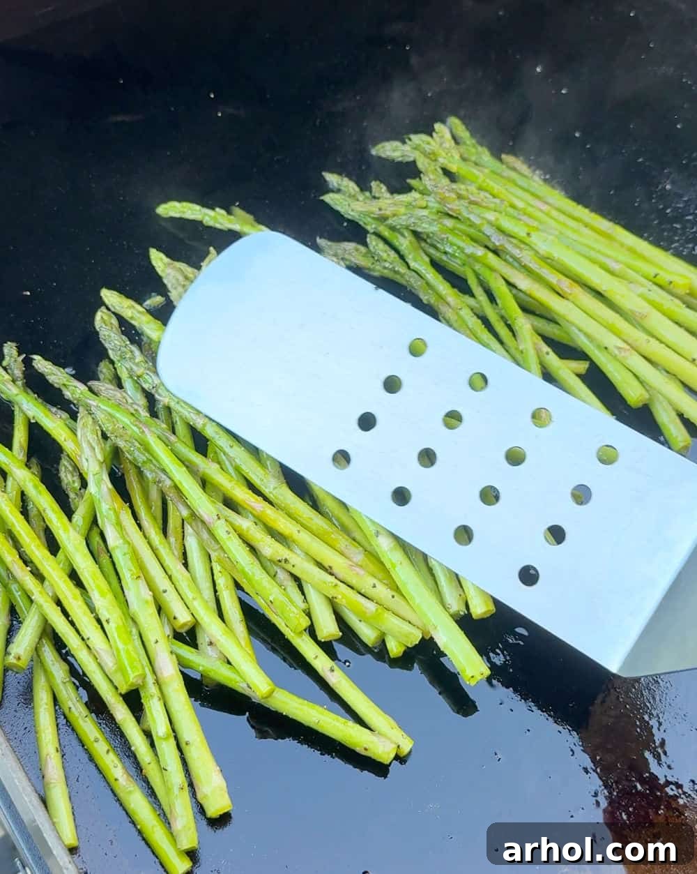 stir asparagus with grilling spatula.