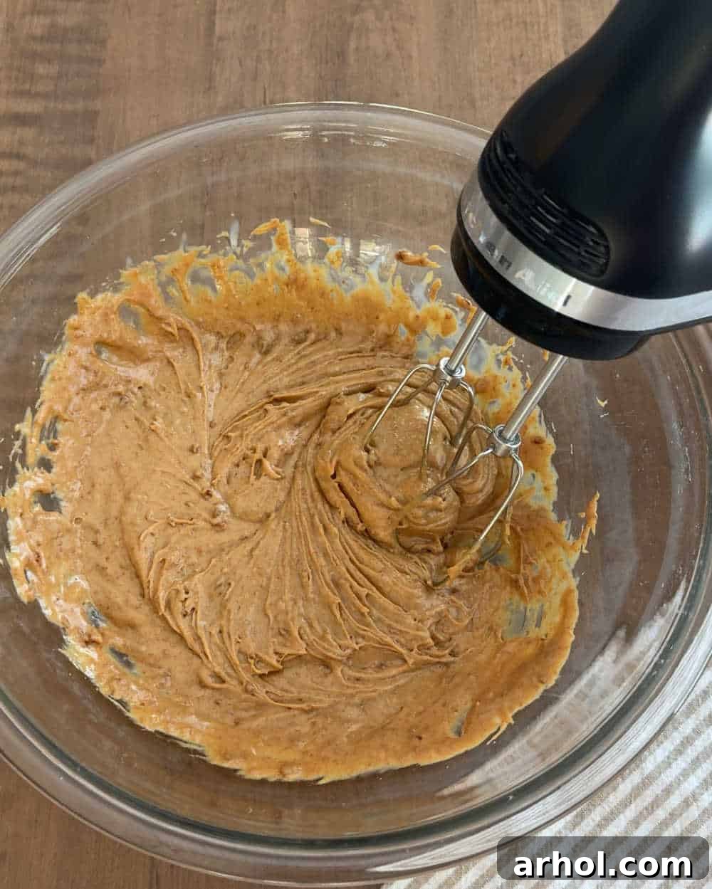 Electric mixer combining cookie butter and sweetened condensed milk in a bowl.
