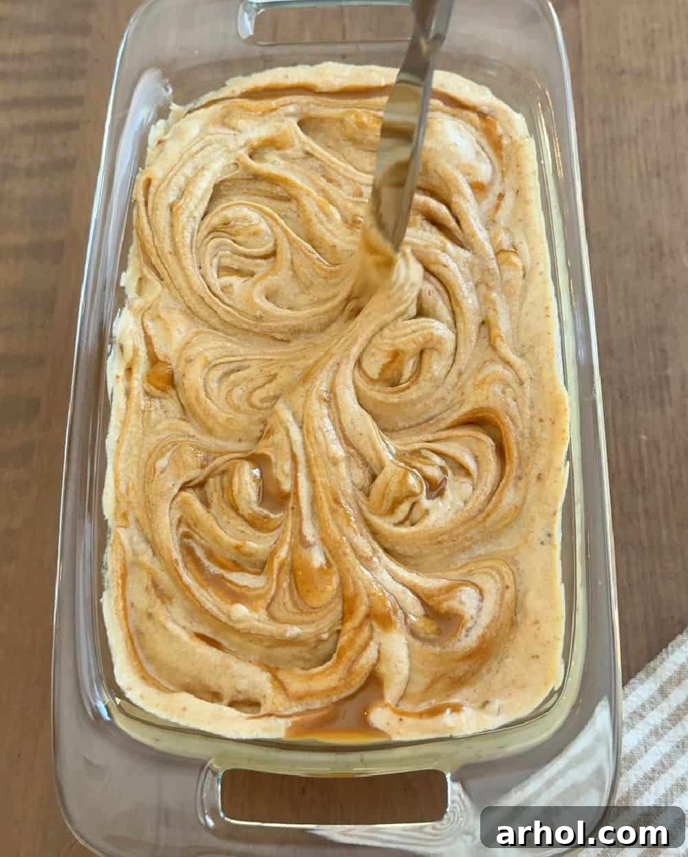 Knife swirling melted cookie butter into the ice cream mixture for aesthetic and flavor.