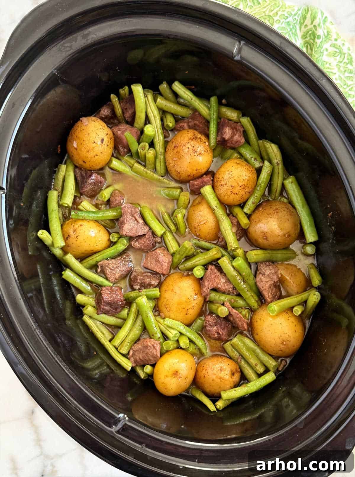 Delicious slow cooker garlic butter beef bites and potatoes with green beans, ready to serve.