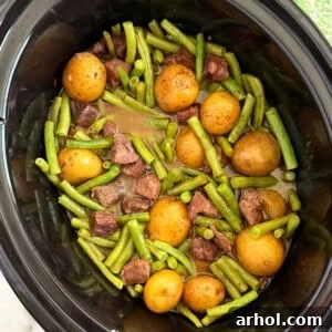 slow cooker garlic butter beef bites and potatoes with green beans in crockpot.