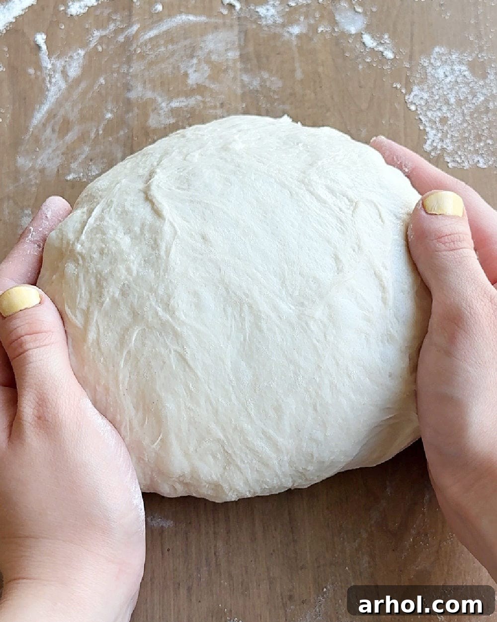 Forming the sourdough dough into a tight, round boule shape by rotating it with cupped hands.