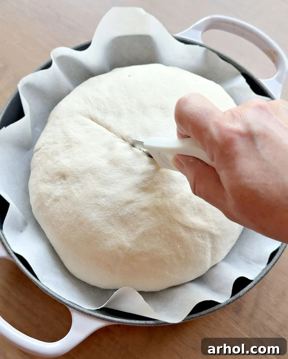 Scoring the sourdough bread with a lame in a decorative pattern just before baking to control expansion.