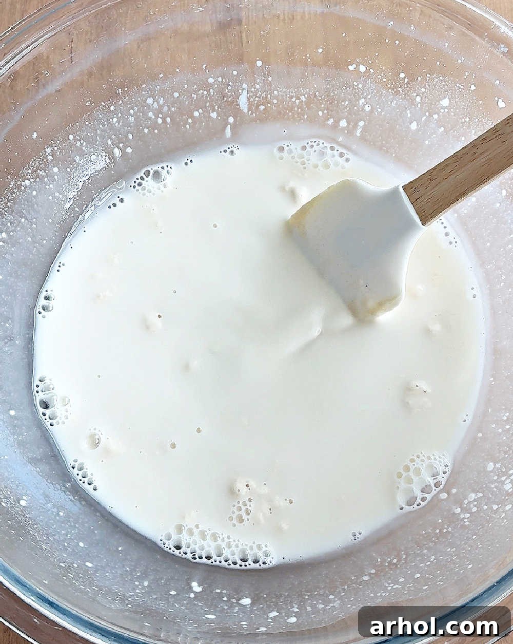 Stirring warm water and active sourdough starter in a large bowl until mostly dissolved.