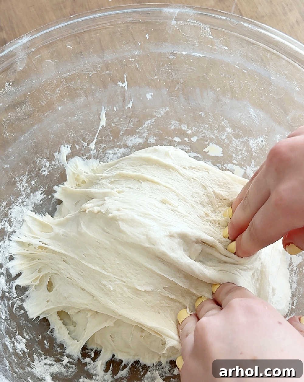 Folding the stretched sourdough dough over itself into the center of the bowl, building strength.