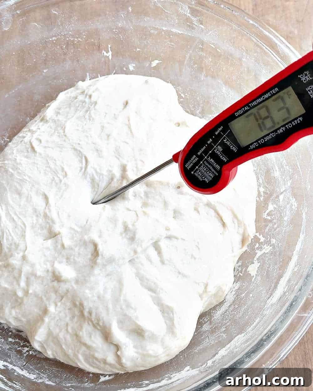 Checking the internal temperature of the sourdough dough with an instant-read thermometer during bulk fermentation to ensure readiness.