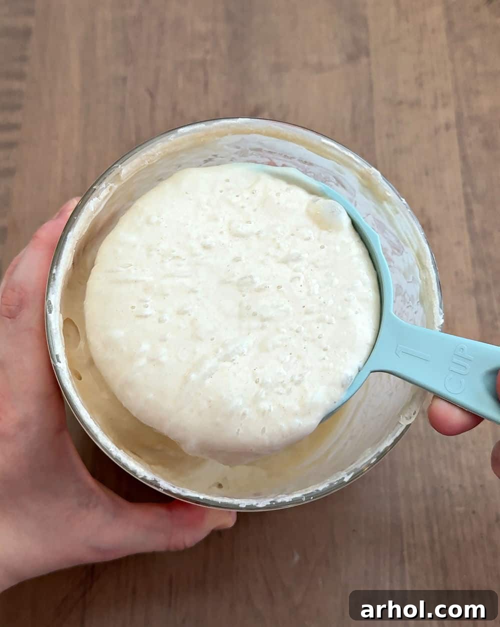 Scooping sourdough starter from the crock into a separate container.
