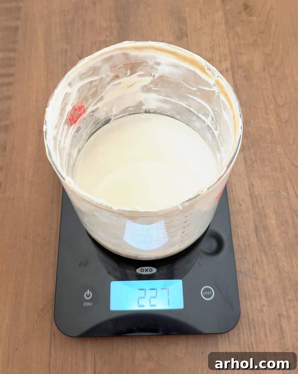 Adding water to the measured sourdough starter in the crock on a scale.