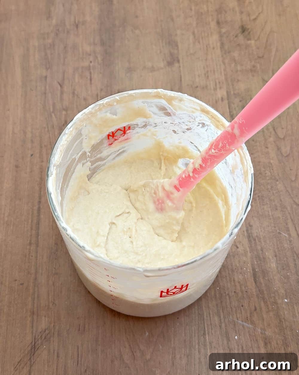 Stirring the freshly fed sourdough starter to combine all ingredients.