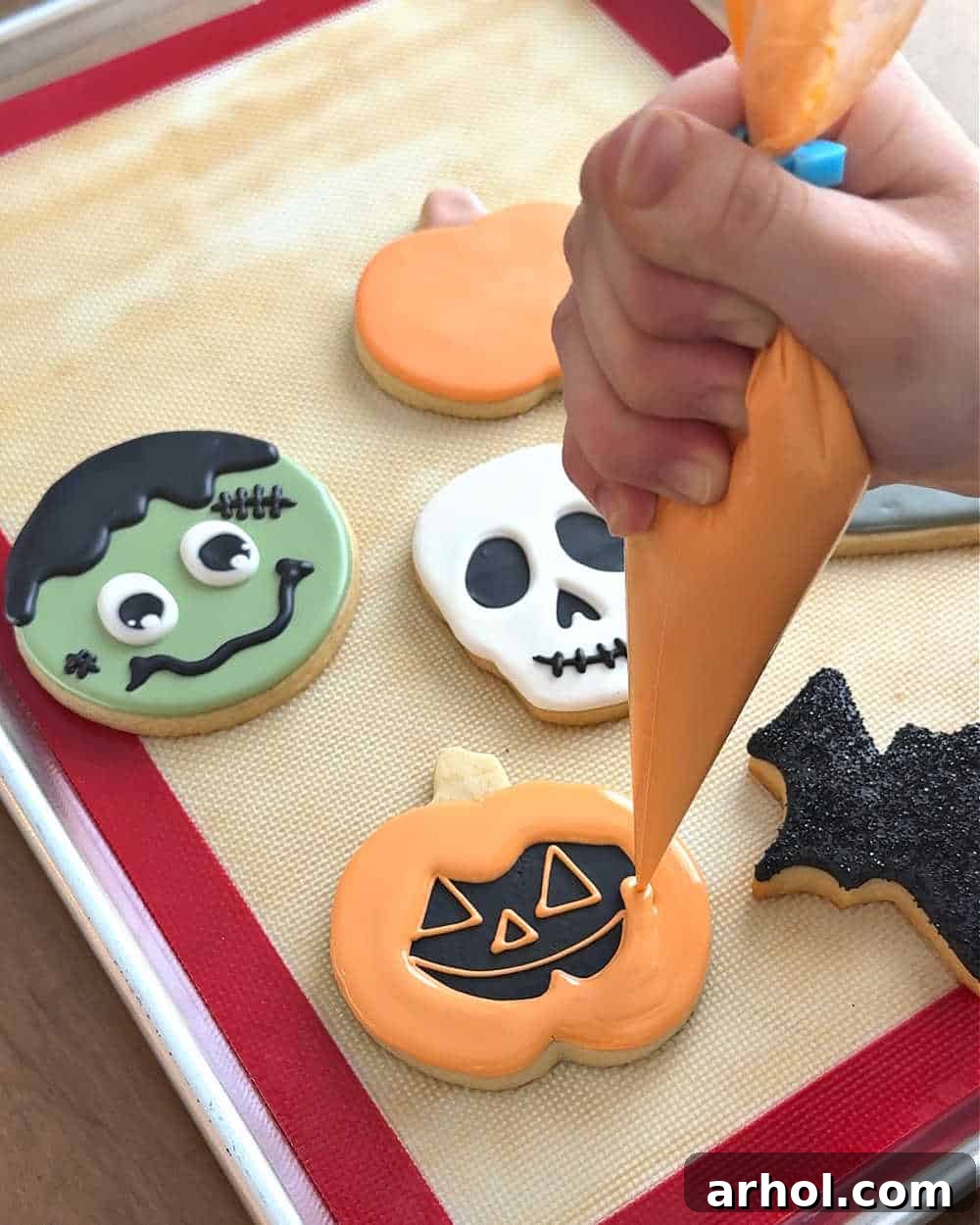 piping icing on pumpkin cookie.