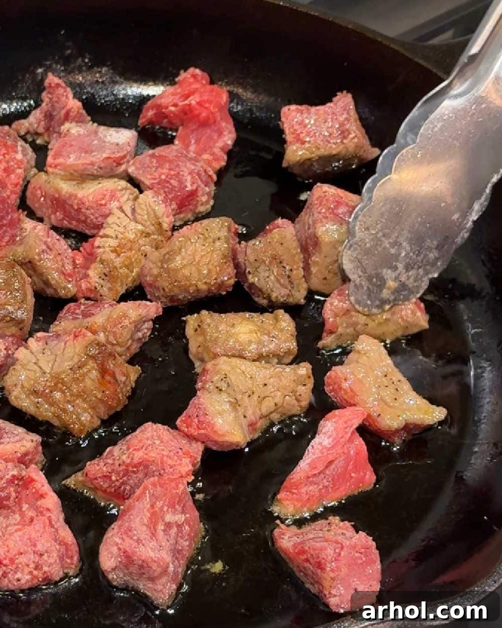 Browning floured beef stew meat in a hot skillet with olive oil to create a flavorful crust.