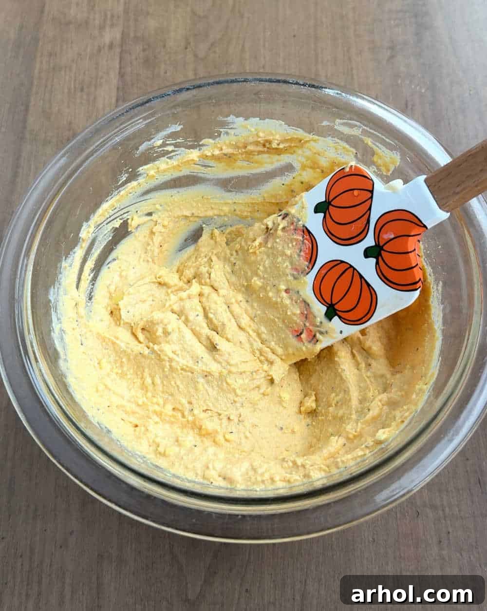 mixing filling ingredients in bowl with pumpkin spatula.