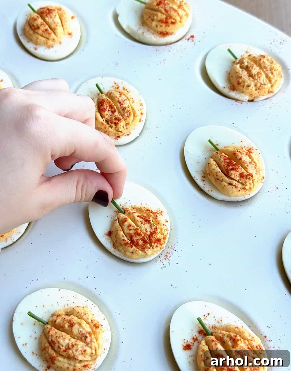 placing chopped chive stem in deviled egg.