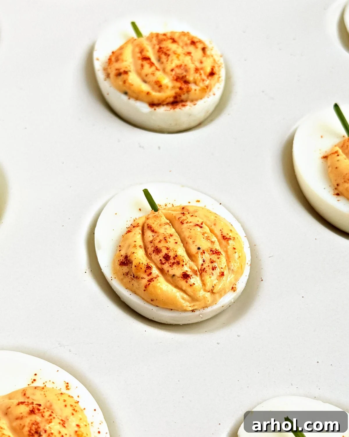 pumpkin deviled egg with paprika and chive stem.