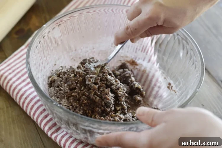 A mixing bowl filled with the dry ingredients—crushed vanilla wafers, ground walnuts, powdered sugar, and cocoa powder—awaiting the liquid additions for the bourbon balls.