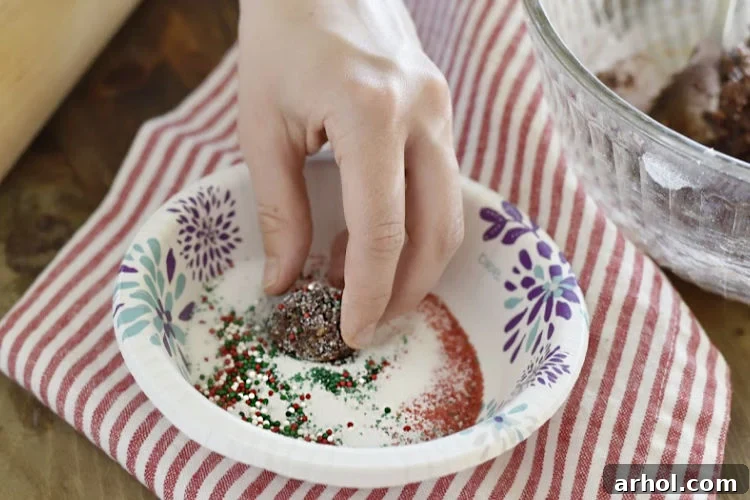 A Bourbon Ball being carefully rolled in a bowl of granulated sugar, creating a beautiful sugary coating before it's ready to be served.