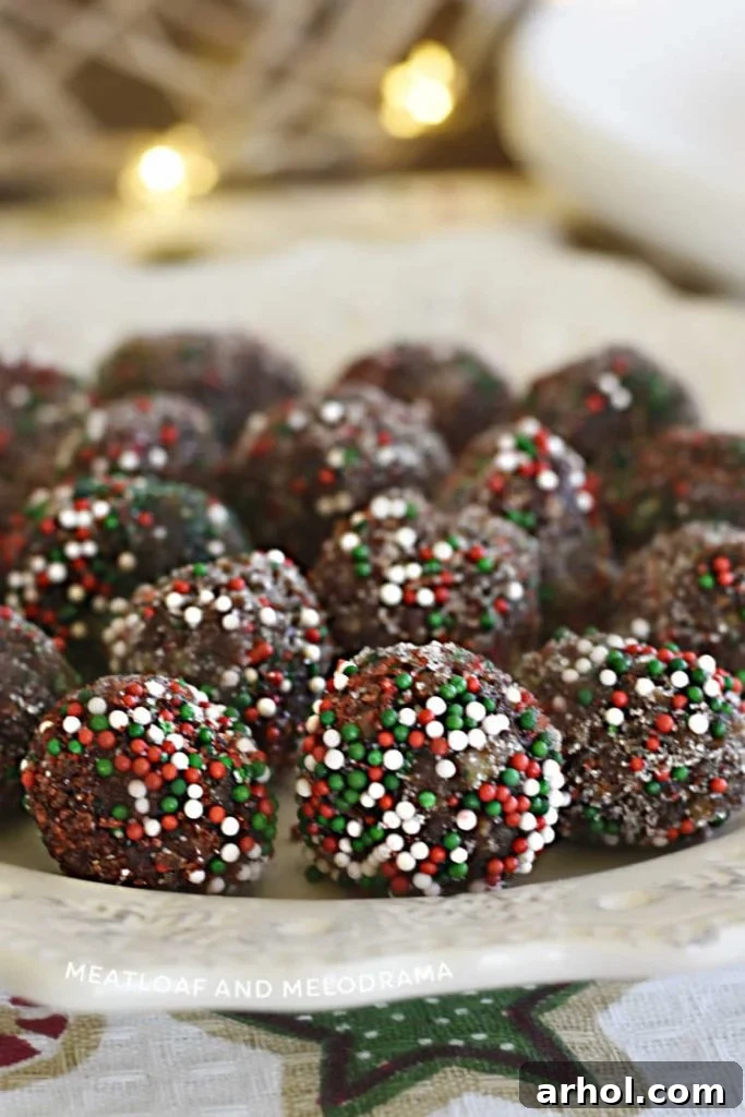 A tempting display of bourbon balls, coated in festive red and green sprinkles, resting on a white plate – an ideal no-bake treat for holiday parties and cookie exchanges.