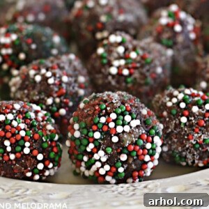 Festive bourbon balls rolled in red and green candy sprinkles on a plate, representing a delicious and easy no-bake holiday treat.