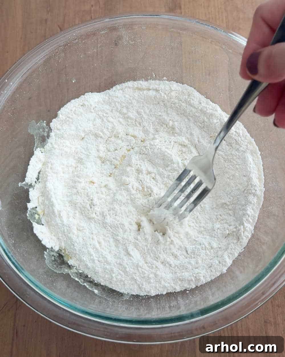 Mixing dry ingredients in a bowl with a fork, preparing for sourdough pancake batter.
