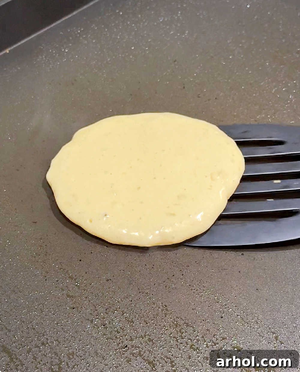 Flipping a golden brown sourdough pancake on a griddle with a spatula, showing the perfect rise and texture.