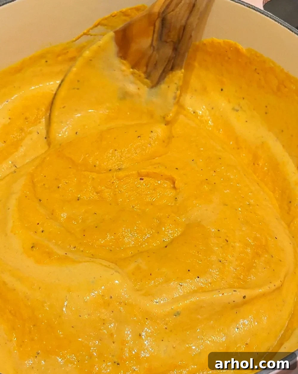 Effortless Pumpkin Pasta Perfection 7 Pouring heavy cream into the simmering pumpkin mixture in the Dutch oven, stirring to achieve a smooth and creamy consistency.