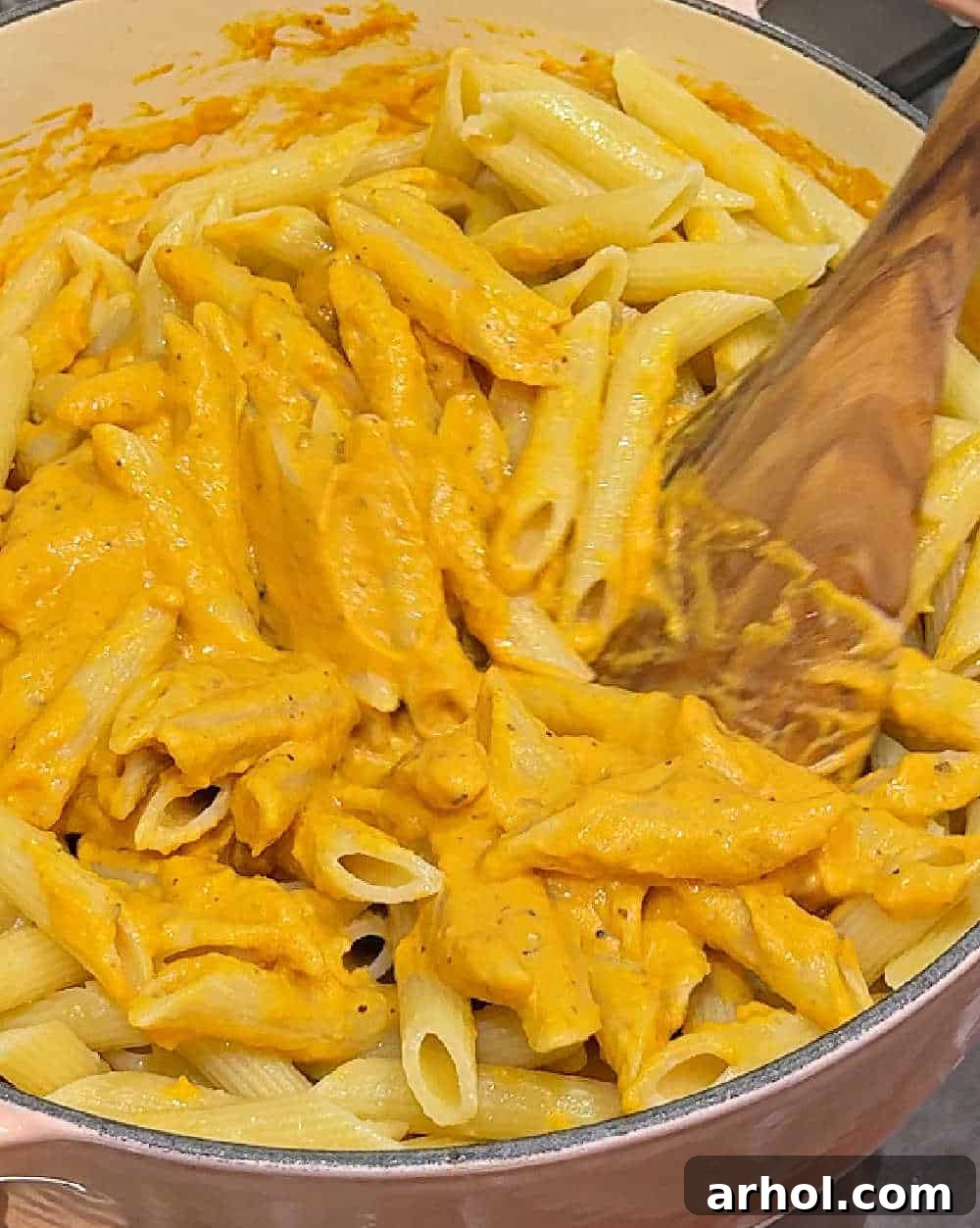 Effortless Pumpkin Pasta Perfection 8 Tossing cooked penne pasta with the freshly made creamy pumpkin sauce in the Dutch oven until every piece is evenly coated.