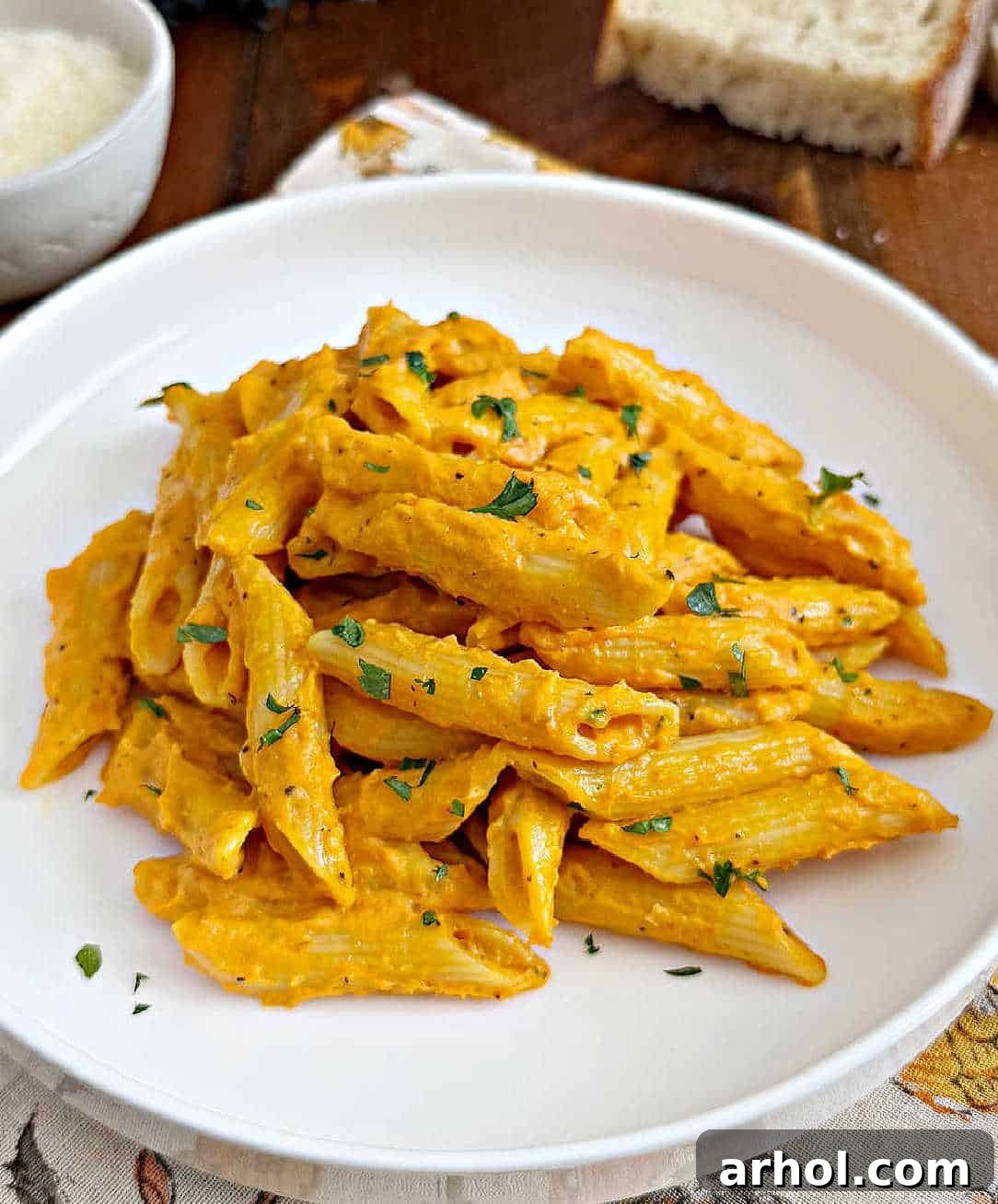 Effortless Pumpkin Pasta Perfection 9 A serving of creamy pumpkin pasta on a white plate, garnished with fresh herbs, showcasing the rich orange color of the sauce.