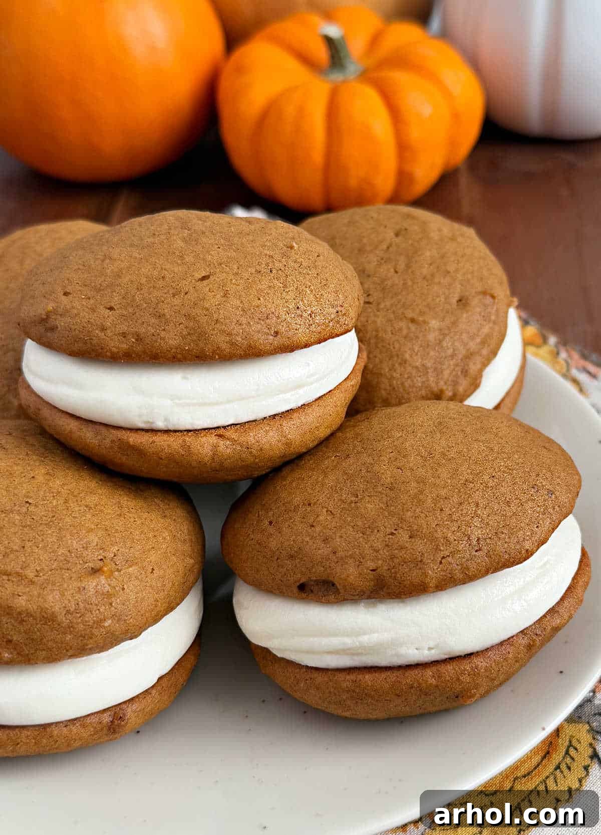 A plate of freshly baked pumpkin whoopie pies displayed on a rustic wooden table, invitingly ready to be enjoyed.