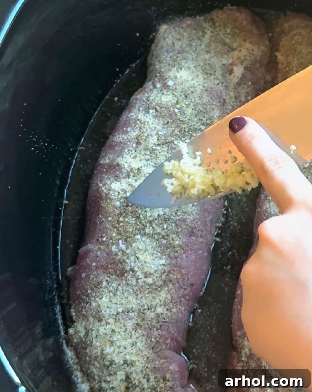 adding minced garlic on meat.