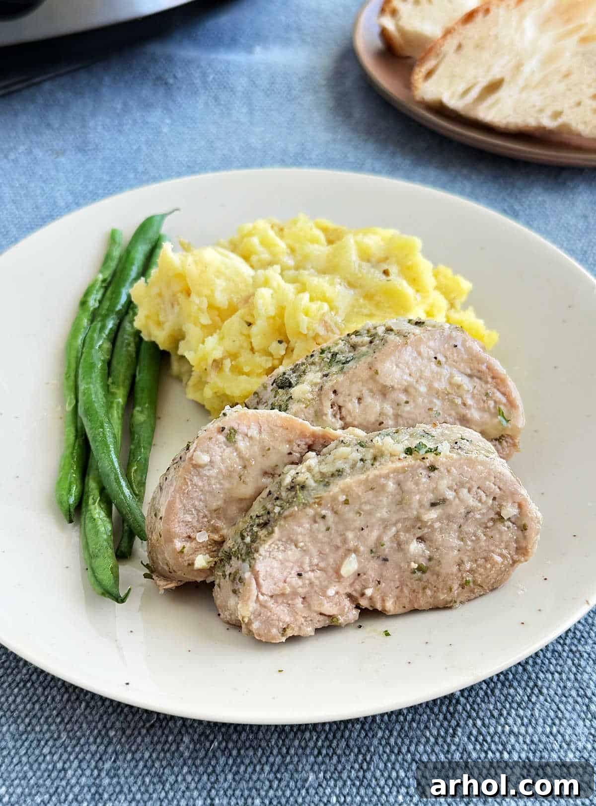 slow cooker garlic butter pork tenderloin with green beans and mashed potatoes on plate.