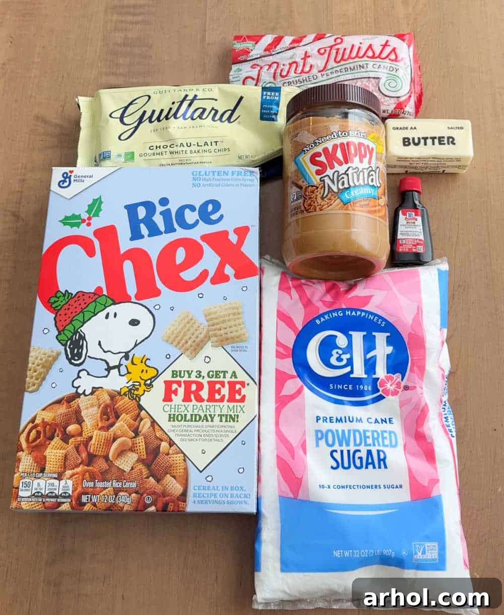 A collection of essential ingredients for peppermint puppy chow, including rice Chex cereal, powdered sugar, creamy peanut butter, white chocolate chips, butter, and peppermint extract, laid out on a rustic surface.