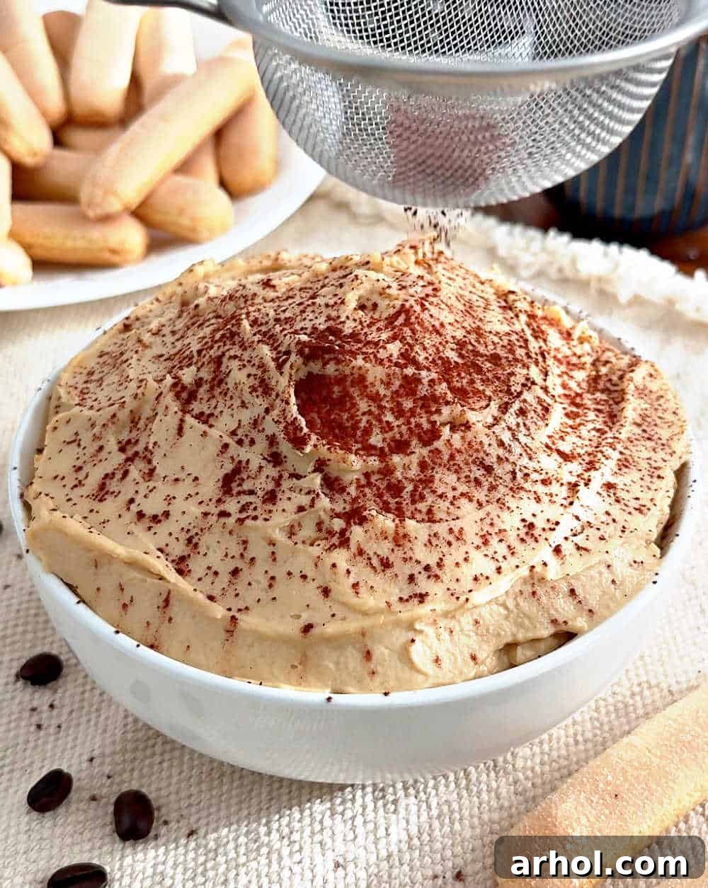 Spoonable Tiramisu Dream 8 A finished bowl of tiramisu dip being delicately dusted with cocoa powder using a fine-mesh sieve before serving.