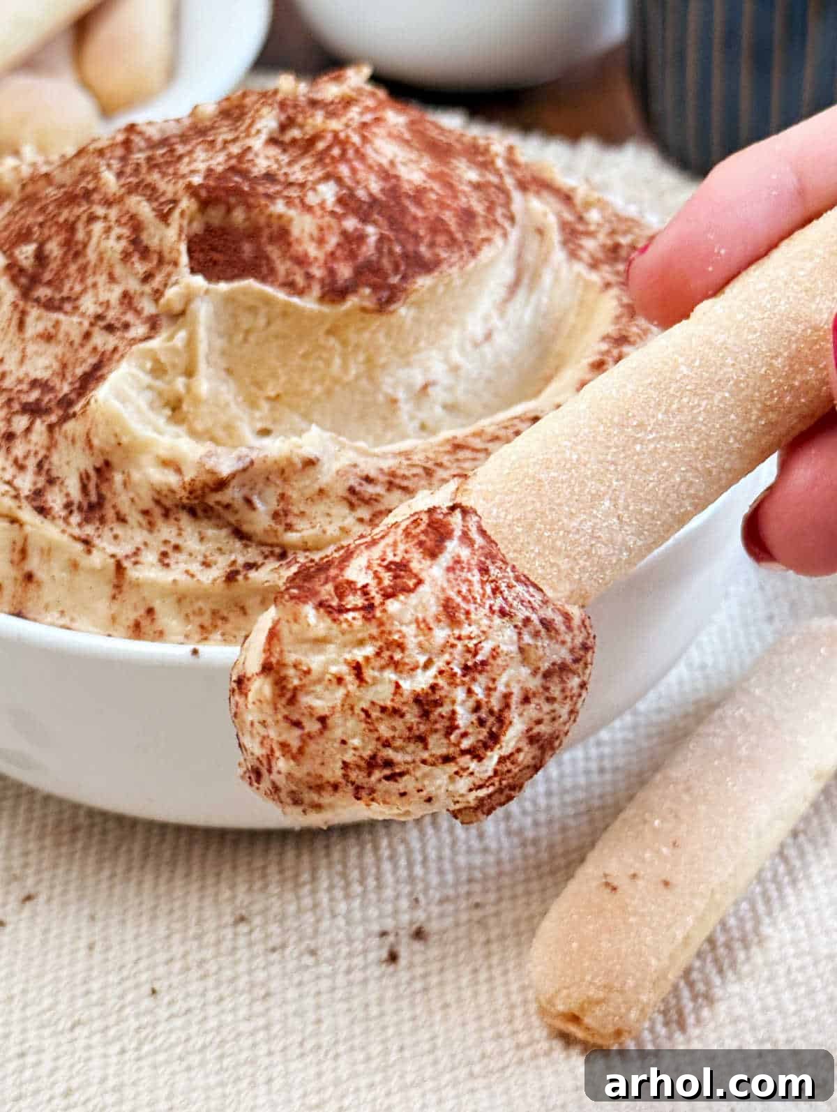 Spoonable Tiramisu Dream 9 A single ladyfinger cookie generously scooped with creamy tiramisu dip, highlighting the perfect texture and inviting presentation.