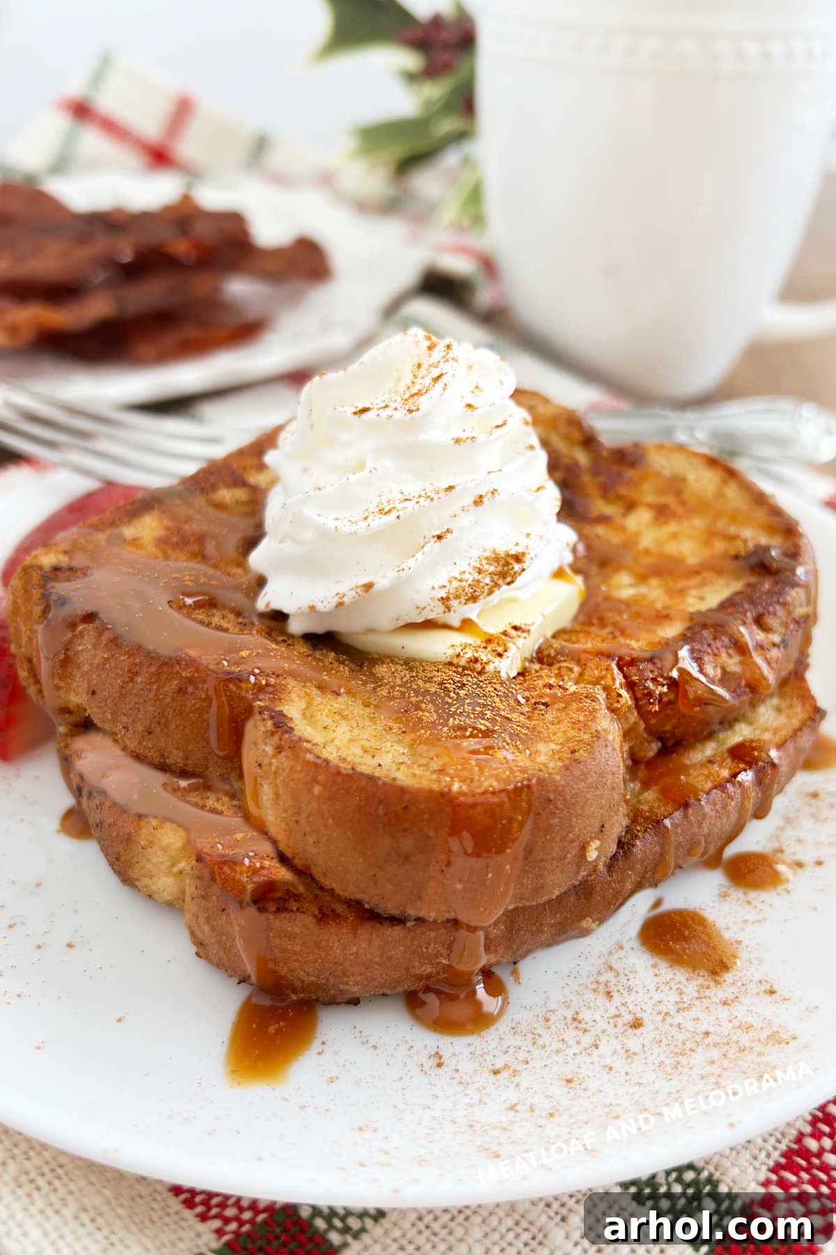 Spiced Eggnog French Toast 2 Golden brown eggnog French toast slices topped with cinnamon and whipped cream, ready to serve on a plate.