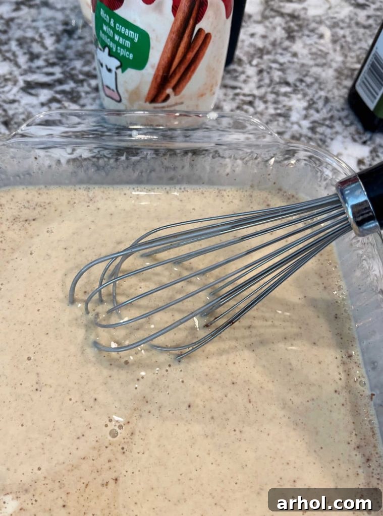 Spiced Eggnog French Toast 4 Whisking eggnog with beaten eggs and spices in a baking dish to create the French toast batter.