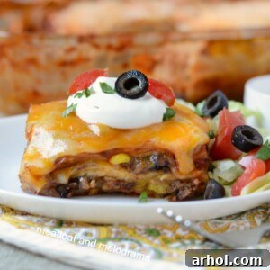 southwestern lasagna enchilada casserole on plate with sour cream lettuce tomatoes and olives