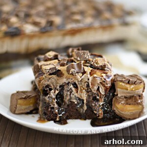 Cosmic Caramel Chocolate Poke Cake 2 milky way poke cake on a white plate with milky way candy bars
