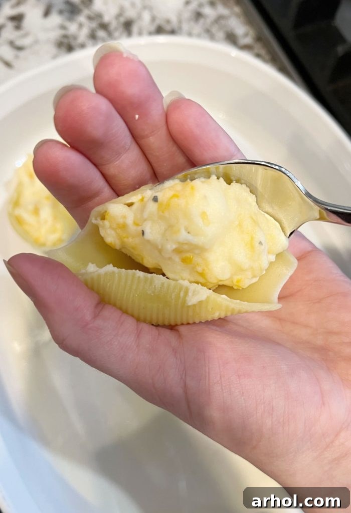 Close-up of jumbo pasta shells being stuffed with cheesy mashed potato filling
