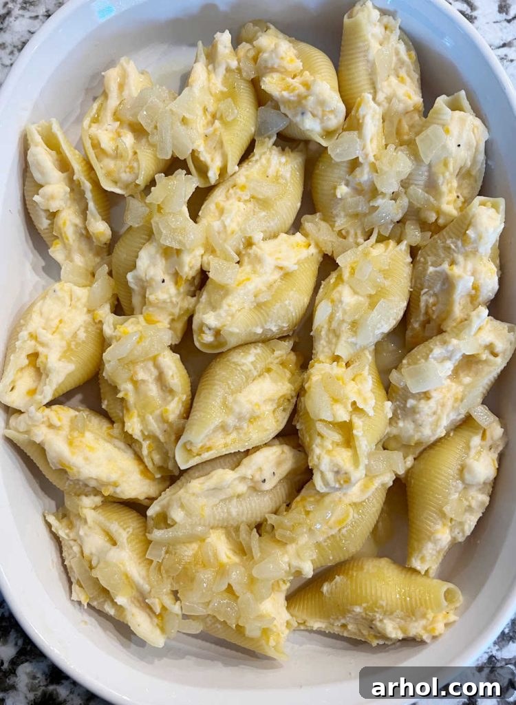 Jumbo pasta shells filled with mashed potatoes and topped with sautéed onions in a casserole dish