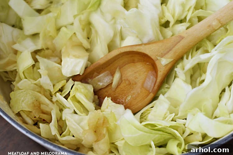 Freshly chopped cabbage and sautéed onions frying together in a large Dutch oven, preparing for the Haluski and Kielbasa recipe.