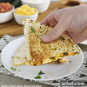 hand holding chicken black bean quesadilla with melty cheese