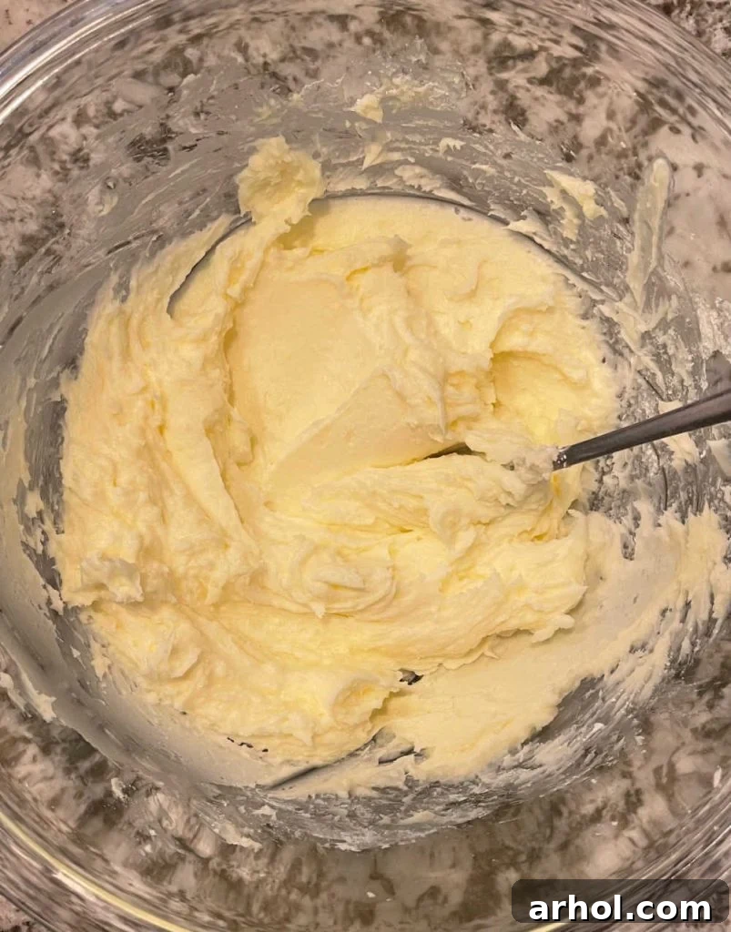 Creaming butter and powdered sugar in a mixing bowl for crescent cookies, creating a smooth, light base for the dough.