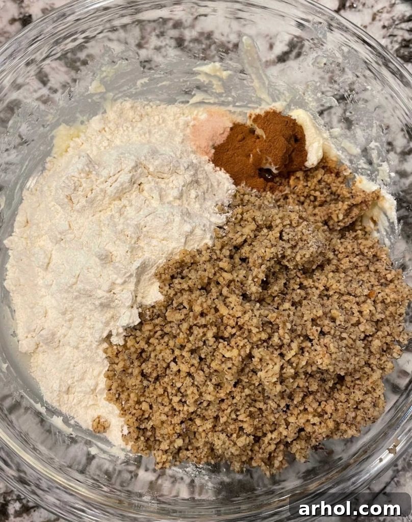 Dry ingredients for crescent cookies, including ground walnuts, cinnamon, and flour, in a mixing bowl.