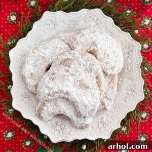 Walnut crescent cookies with powdered sugar on white plate, ready to be served.