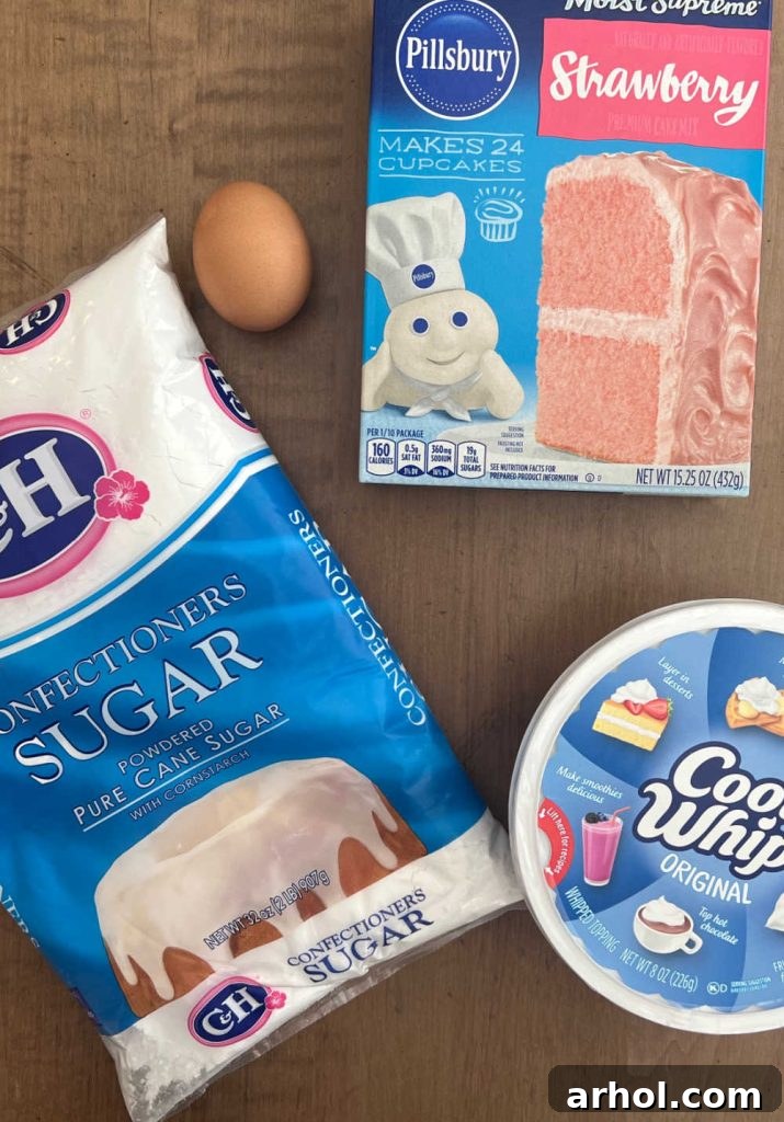 The four simple ingredients for strawberry crinkle cookies: a box of strawberry cake mix, a tub of Cool Whip, one large egg, and a bowl of powdered sugar.