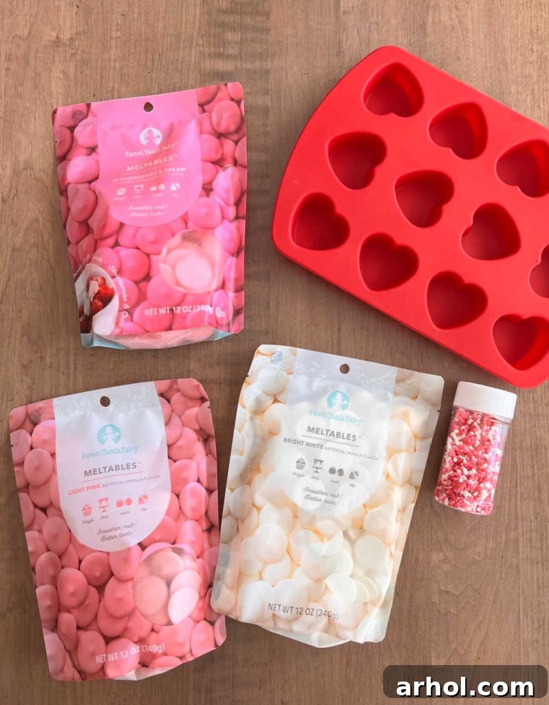 Colorful candy melts, assorted sprinkles, and a heart-shaped silicone candy mold laid out on a table, ready for crafting homemade chocolate hearts.